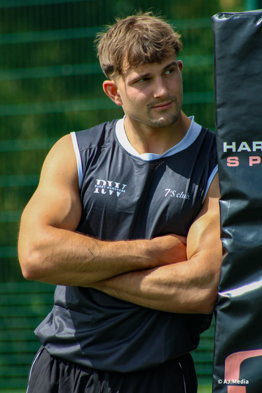 Man in athletic wear standing with arms crossed against a green background